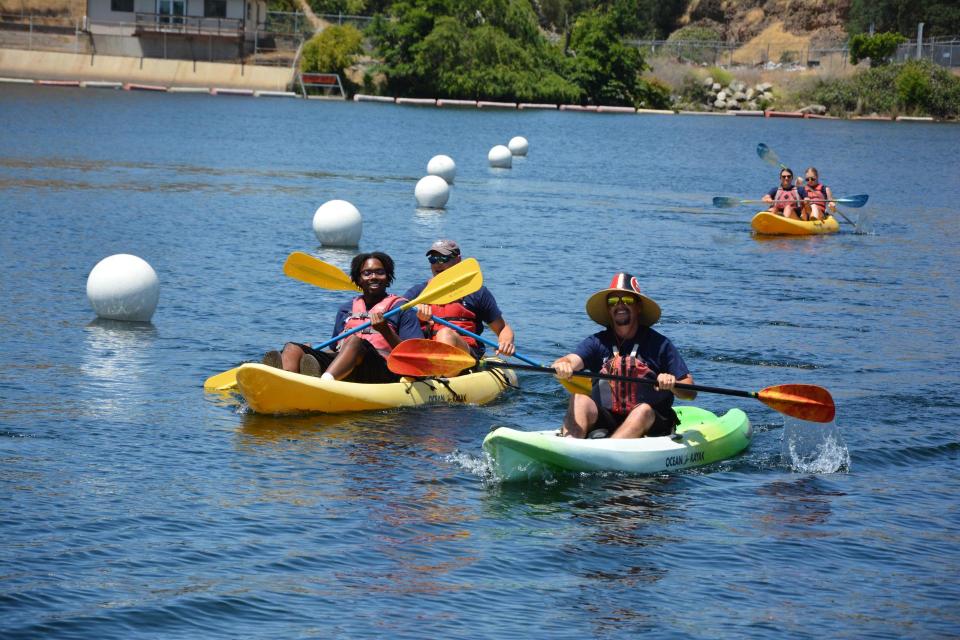 one person in a single kayak and two people in a tandem kayak on lake Natoma