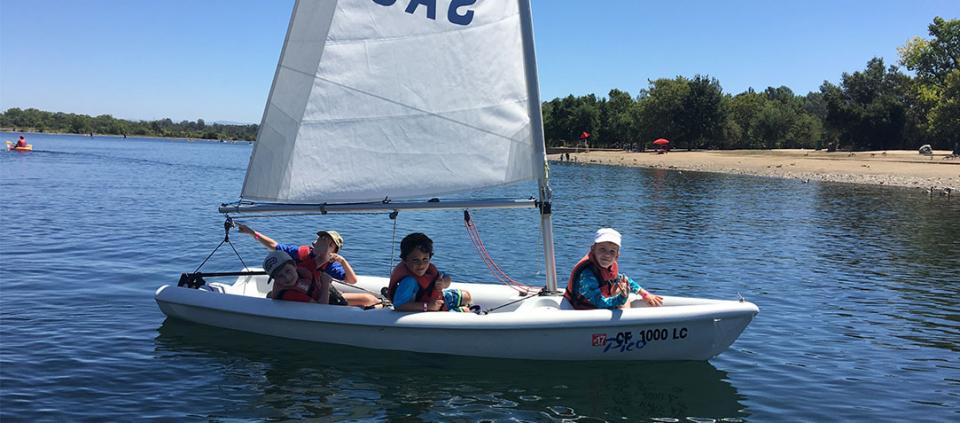 kids in a sailboat smiling at the camera